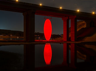 Spanish artist Spy's Oviod (2024) on display in the Wadi Hanifah, Riyadh Saudi Arabia at night, a huge, glowing red egg suspended under a bridge