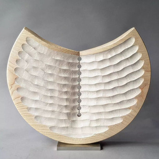 Abstract wood art sculpture with wood carvings reminscient of a geometric design.