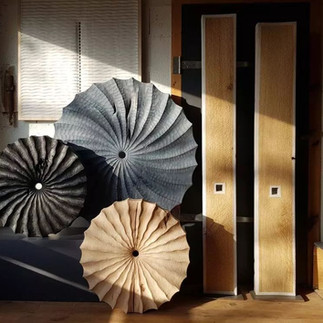 abstract wood art sculpture placed in front of contemporary wood panels in the artist's studio