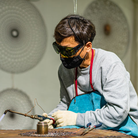 image of local japanese artist commissioned by artelier art consultancy showing him welding in his studio to make a metallic wire art piece for a feature wall