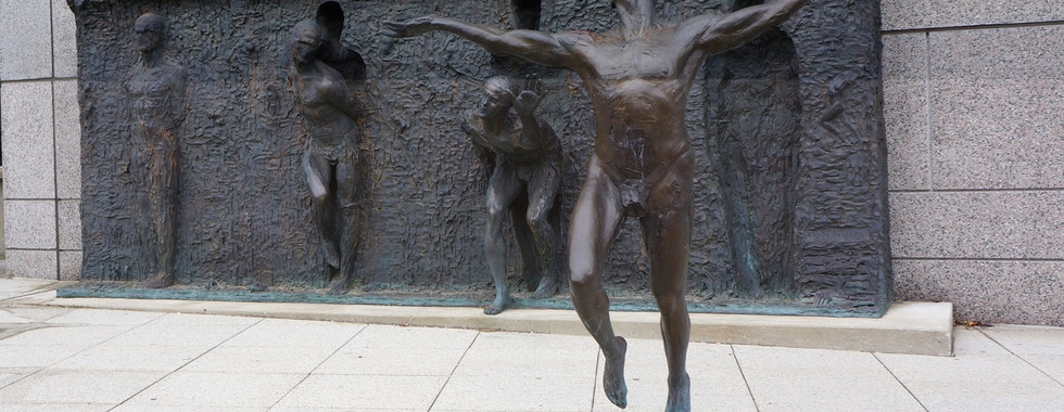 30. © 4 bronze sculpture figures emerging out of a wall in a celebratory and dancelike way