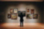 Generic moody image of a person standing in front of a collection of artworks in a museum space with vignette editing