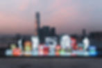 the artist vhil's artworks displayed in an outdoor light exhibition with a sunset backdrop of the city