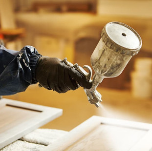 in a workshop a spray painter lases fire resistant paint onto a piece of wood