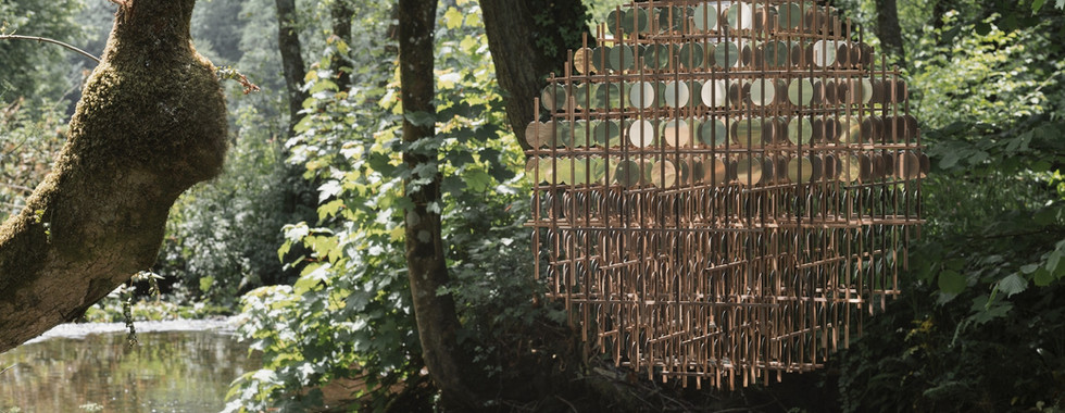 art installation above a british river made of golden coins in a sphere shape