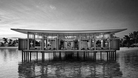 luxury maldivian hotel resort by rosewood coming in 2025 featuring contemporary architecture on wooden stilts above the tropical water taken in a black and white photograph