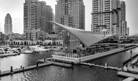 black and white image of the corinthia yacht club in doha qatar by the harbour feauturing a contemporary building