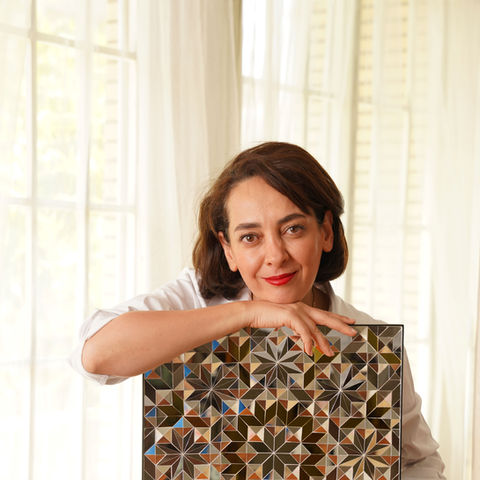 artist maryam shekarchian, an artist based in iran who specialised in geometric glass tiles mirror posing with her artwork