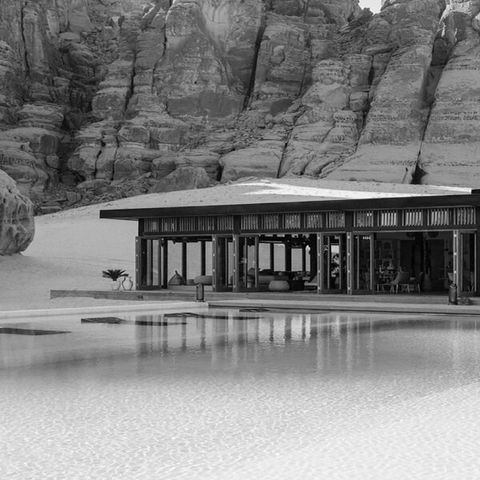 outdoor image of alula resort hotel in saudi arabia showing a wooden contemporary building, a pool and the desert behind