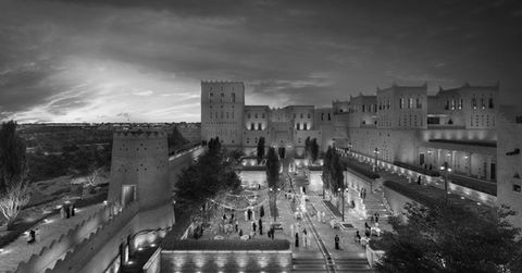 black and white image of raffles hotel at night at diriyah gate, saudi arabia featuring local saudi architect renovated with crowds of people engaged in the marketplace area