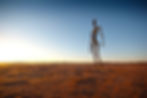 A large slender figure stands isolated against a desert backdrop.