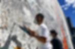 two artists engrave into a cement wall in the process of commissioning a large scale portrait using heavy duty machinery