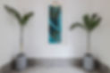 in situ image of a hallway with two trees sitting either side of a ceramic wall installation in turquoise blues imitating the leaves of a palm located in raffles al areen palace, bahrain