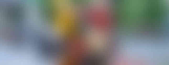 60. © Photo by Nick West showing an above human size garbage bin trash can filled with leading industry brand packaging like coca cola in a japanese urban space, left to the artwork is a business suit man with a suitcase and another business suit man with an umbrella in front of a parking lot and right to the can are 3 orange traffic cones