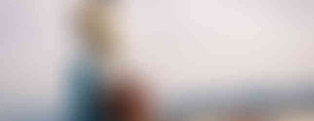 18. © Photo by Pat_4light showing a human figure sculpture looking over the water of a port carrying a suitcase but parts of his body are missing such as his torso and upper leg