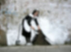 A Banksy public art mural featuring a maid sweeping the dirt under a manmade painted wall to imitate a large fabric textile hanging from the brickwork