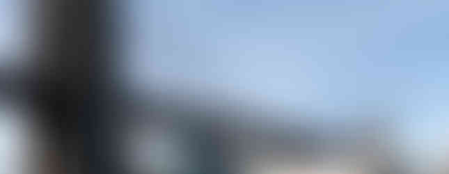 © Photo by John Hill showing an art installation of triangular metal sculptures below a new york bridge in daylight