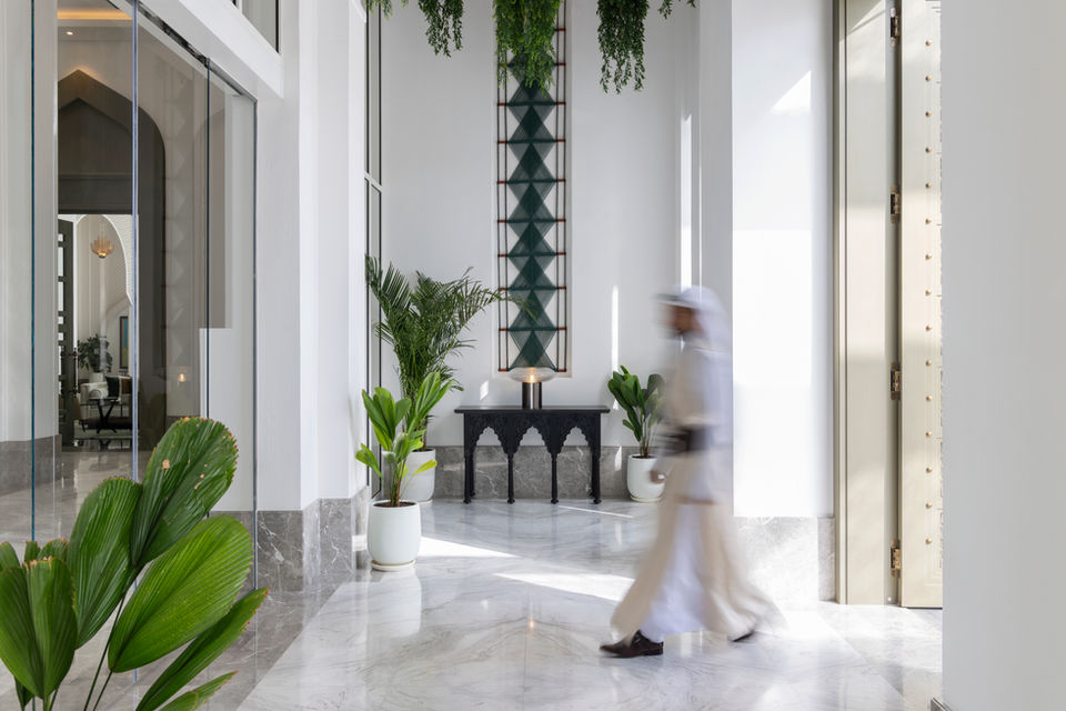 exemplar art work from artelier's art collection at raffles al areen palace, bahrain, featuring a bahraini man walking in a blurred motion in front of a woven green wall piece tapestry