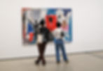 2 individuals standing in front of a basquiat artwork in a gallery display