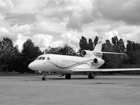 Outdoor image in black and white of an aircraft in the sky that had artwork commissioned by Artelier called DASSAULT FALCON 7X by Jet Aviation, Basel