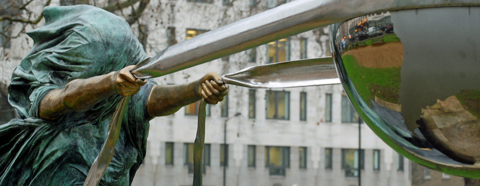 21. © Photo by It's No Game showing a veiled oxidised copper sculpture human figure pulling tightly on a stainless steel globe in the middle of an urban space zoomed in