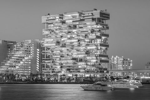 outdoor shot at night in black and white of dorchester collection hotel in dubai, uae in a contemporary building made of layered glass