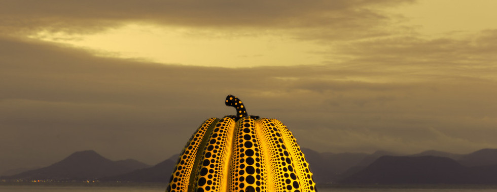 57. © Photo by Alex Stoen showing a contemporary art installation of a yellow dotted squash pumpkin shape overlooked a lake in japan in the evening