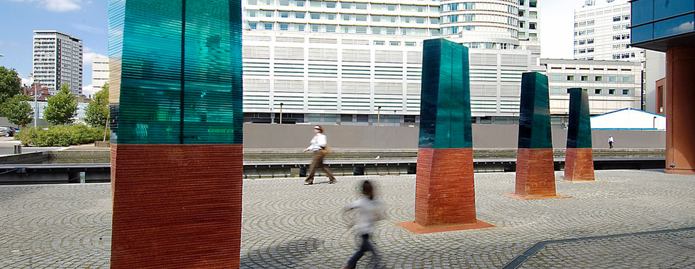 child running between to contemporary glass and copper structures in london near paddington station by the river