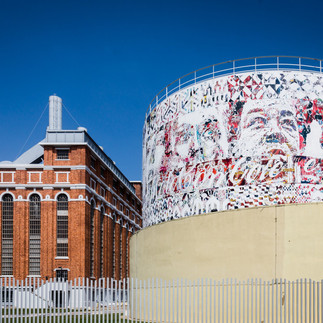 © Vhils's public art display next to an industrial factory where his coca cola / portrait collage is fixed on a circular dome