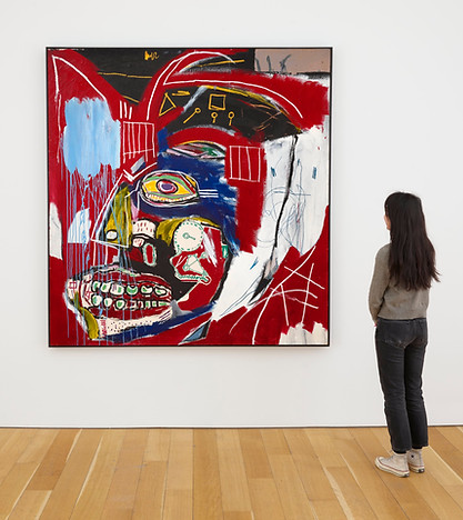 a young woman in a gallery setting looks at an Art dealer's display of Jean-Michel Basquiat