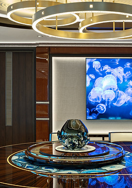 Interior design image of LUSINE HEESEN YACHTs Photo by DC featuring artworks curated by artelier featuring a mahogany table, handle carved glass sculptures with modernist ceiling lights and a jelly fish art display in the background