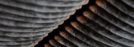 wooden artwork in dark burnt wood coming towards the centre to showcase a burnt orange relief