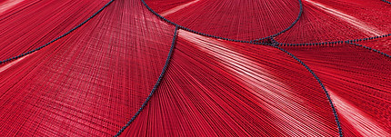 red woven wire artwork in an abstract curved style. light filters off the wire artwork.