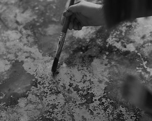 black and white image of a hand painting an abstract golf leaf canvas artwork with a paintbrush