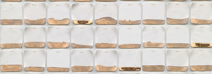 a graph-like plaster artwork showcasing many small white rectangular ceramic pieces, with gold tips at the bottom.