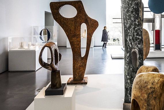 Indoor image of the Hepworth Wakefield feature a contemporary minimalist abstract sculpture exhibition with styles imitating henry moore and barbara hepworth, a visitor walks in the background