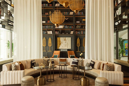 example of Working With Hospitality Art Consultants with artelier art consultancy featuring a large scale curation project for raffles al areen palace, including 4 golden arabic calligraphic spears, a gold leaf map of bahrain the country, a semi circular white sofa with brown and white cushions and a ceiling-height library