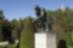 Rodin's 'The Thinker', an iconic piece of installation art in a countryside setting.