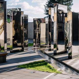 Artelier public art consultants curate a mirror garden in a sculpture park with gemotric forms reflecting the trees and casting shadows on the concrete.