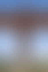 A close-up of angel of the north, figure in bronze with arms cut off and two people viewing it in the front.