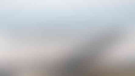A close-up, panaromic view of Spiral Jetty by Robert Smithson, with people in the foreground surrounding the spiral land art installation on a cloudy day.