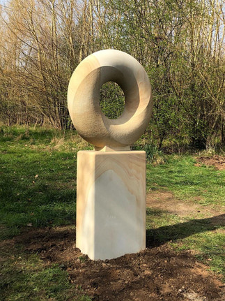 This minimalist art sculpture is a public artwork depicting a circular structure on a plinth.