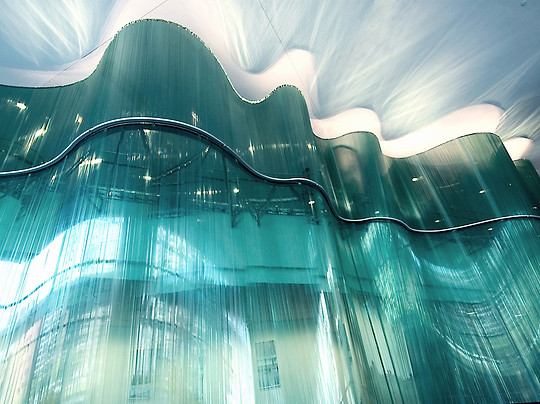 an upwards photograph looking at the curves, shadows and colours of danny lane the sculptor's wave light feature wall sculpture covering the entirety of the building's interior 