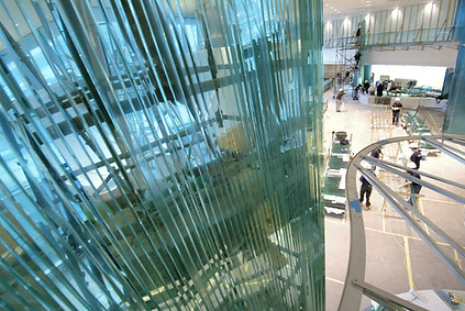 side angle image of danny lane's glass mural wall sculpture being installation in a lobby entrance of a corporate building