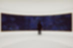 backshot image of person looking at a curved wall artwork in a panoramic dark blue style