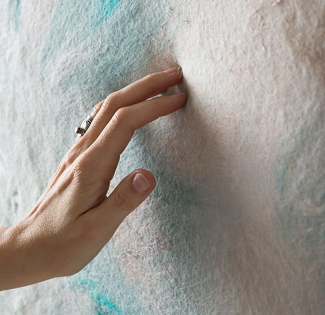 Laurine Malengreau felt artist touching her blue and white textured felt artwork up close, the french artist is represented by the UK art advisor artelier art consultancy