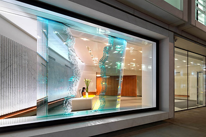 Example of Danny Lane's glass feature wall sculptures on display in a corporate office setting at night in london