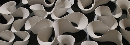 white plaster artwork showing undulating curves of the sculpture set against a black wall.