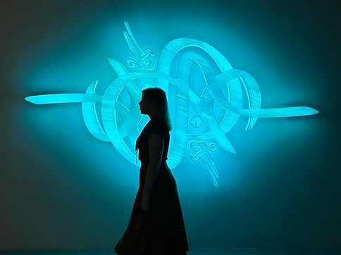 A member of the artelier team walks past a light art festival new media installation organised by noor riyadh 2023 in collaboration with artelier, in a dark room with neon blue lights