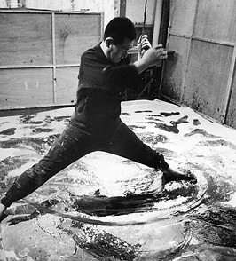 in action black and white photo shot of Kazuo Shiraga doing a live performance abstract painting art on the floor to represent the 'artist research & concept development' phase of artelier's services